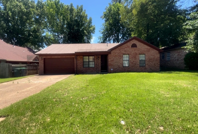Brick exterior with a peaked roofline, a visible garage door, and a concrete driveway