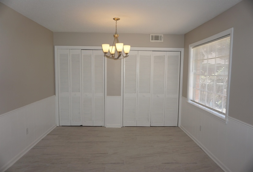 Room featuring wood-finish flooring, neutral wall tones, and white wainscoting