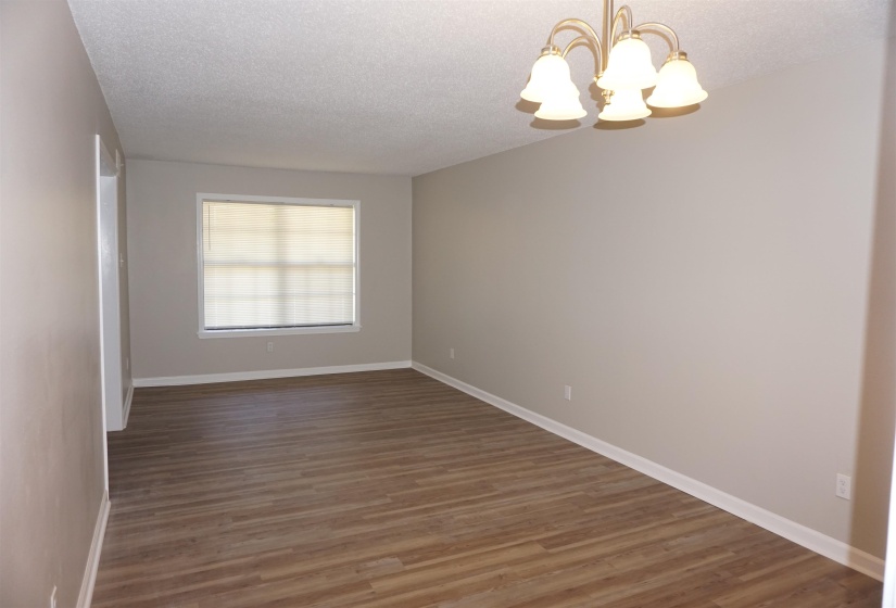 Spacious interior room featuring wood-finish flooring, neutral wall tones, and white baseboards