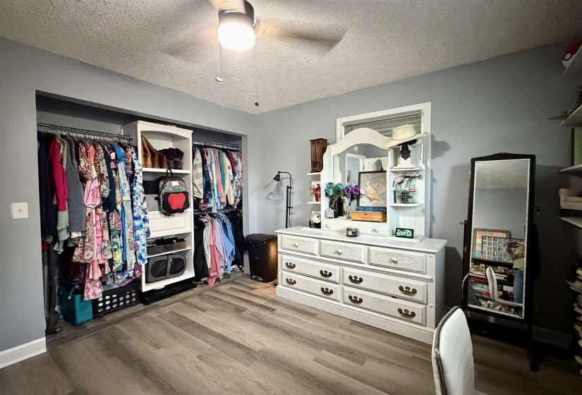 Spacious room featuring wood-finish flooring, a ceiling fan with integrated lighting, and a window with white trim