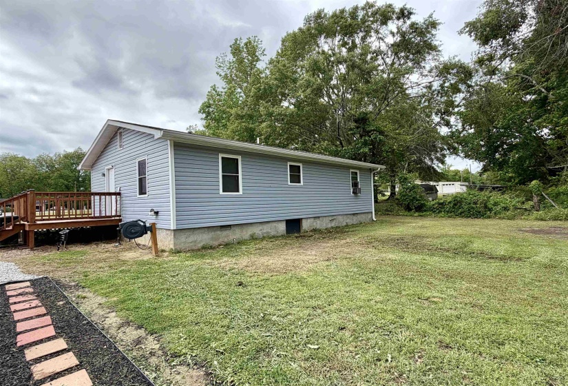 Light blue vinyl siding exterior with a wood deck, a white-framed window, and a concrete foundation