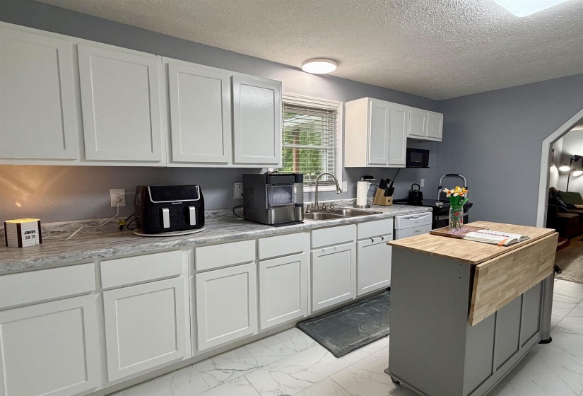 Kitchen featuring white shaker-style cabinetry, grey-veined countertops, and a white tile floor