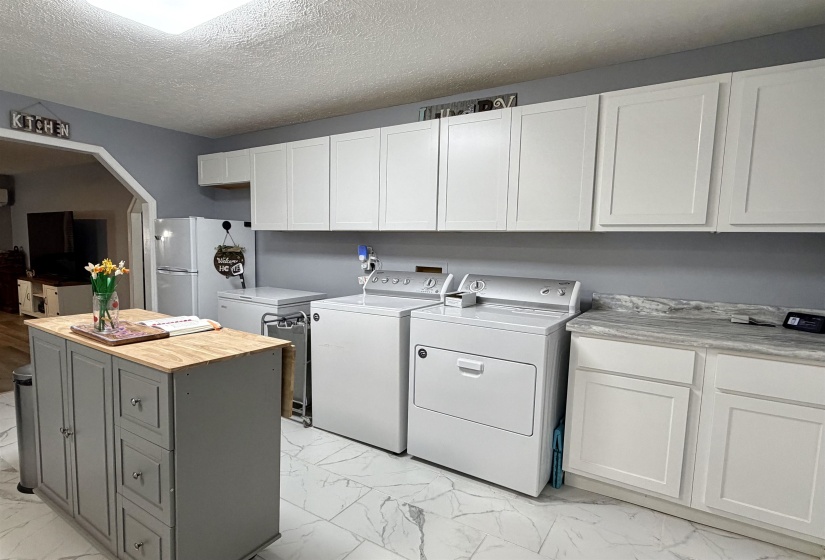 Modern utility space featuring white shaker-style cabinetry, a built-in countertop, and white tile flooring