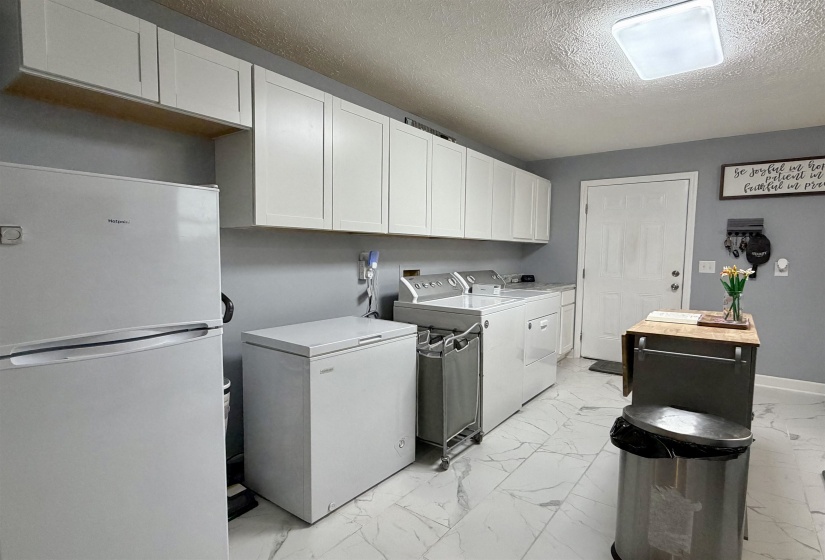 Laundry area featuring extensive white shaker-style cabinetry, a built-in sink, and wood-finish countertops