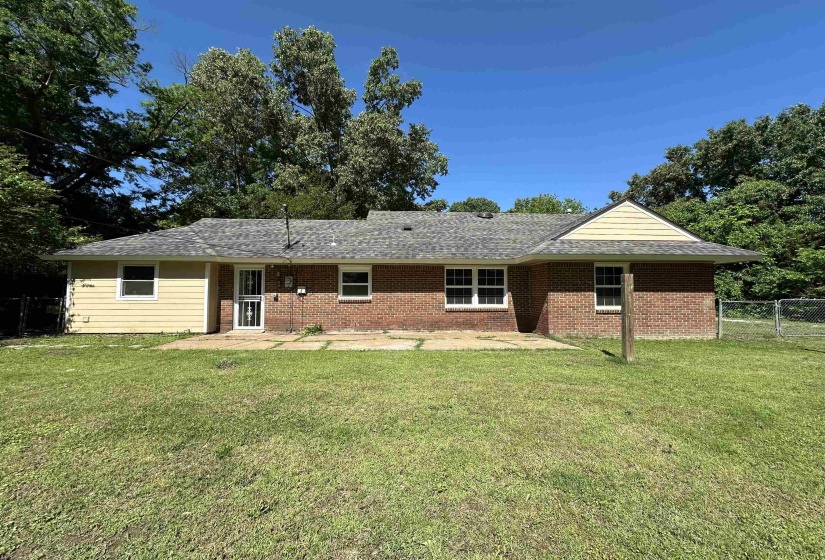 Exterior featuring a blend of brick and horizontal siding, a shingled roof, multiple windows, and a paved patio area