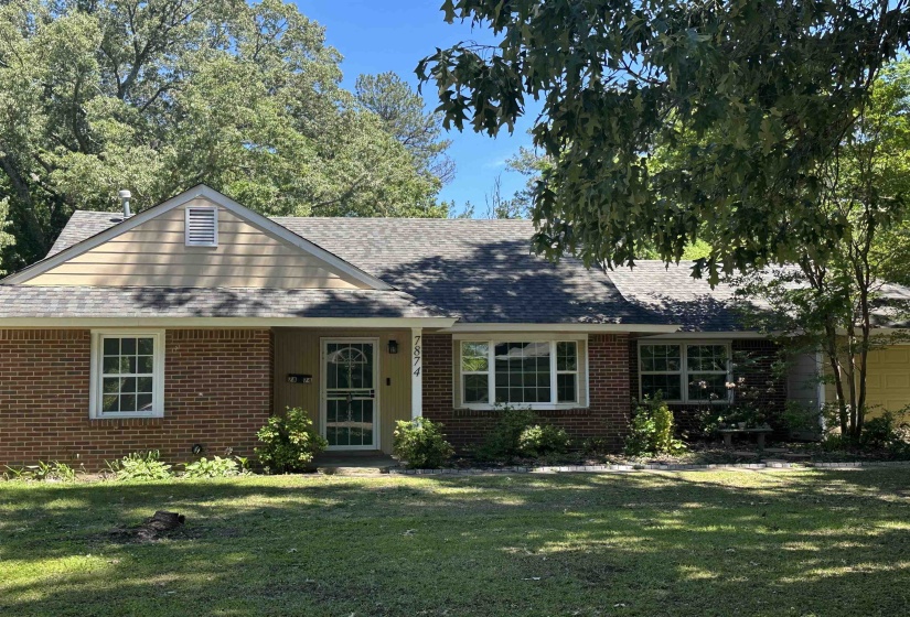 Brick ranch-style residence featuring a prominent gable roof with shingle siding