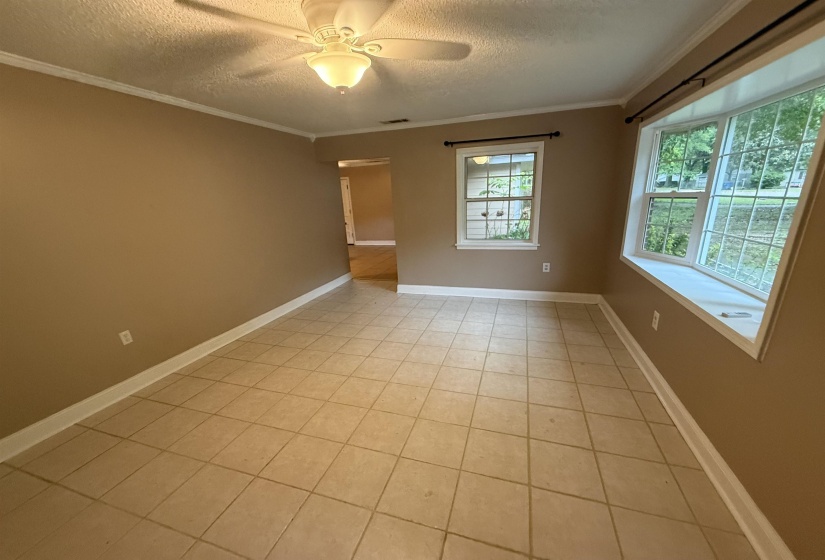 Spacious room featuring neutral paint, tile flooring, a ceiling fan, and a prominent bay window