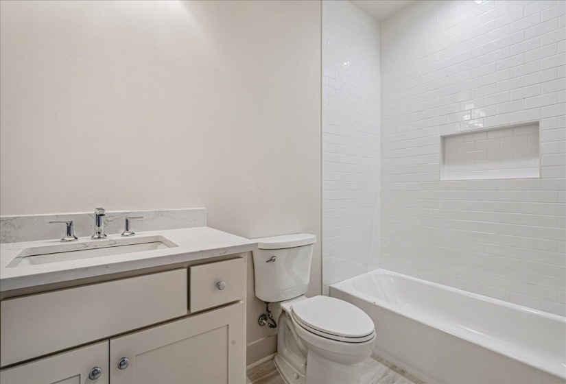 Bathroom featuring a white subway tile shower, built-in shower niche, white soaking tub, light-colored vanity with a built-in sink, and polished chrome fixtures
