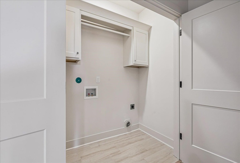 Dedicated laundry space featuring wood-finish tile flooring and crisp white walls
