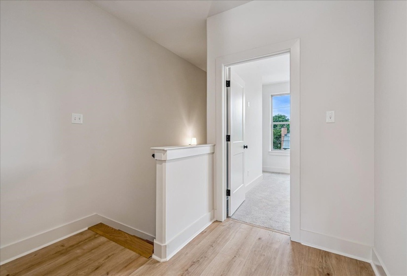 Upper-level hallway featuring wood-finish flooring, white baseboards, and a white half-wall railing