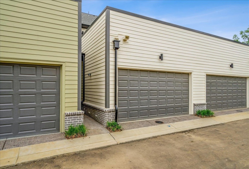 Exterior featuring multiple panel-style garage doors, horizontal siding, and brick accents