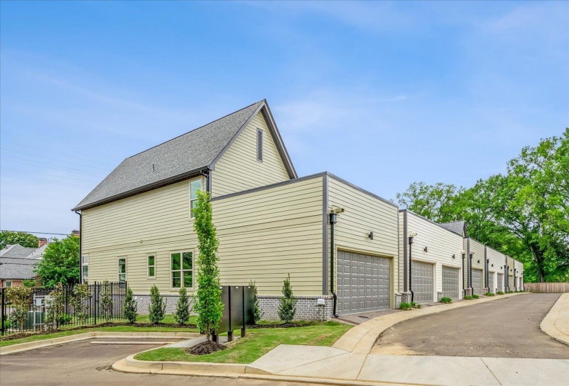 Exterior featuring light-colored horizontal siding, a dark shingle roof, and a series of attached garages with dark gray doors