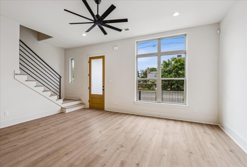 Open-concept living space with wood-finish flooring, a contemporary black ceiling fan, and recessed lighting