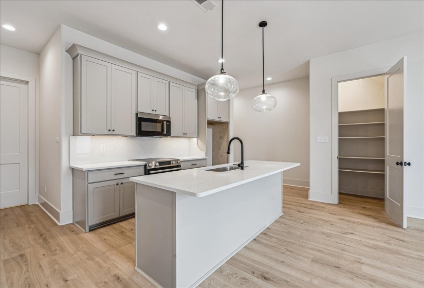 Contemporary kitchen featuring light gray cabinetry, quartz countertops, a white subway tile backsplash, and wood-finish flooring
