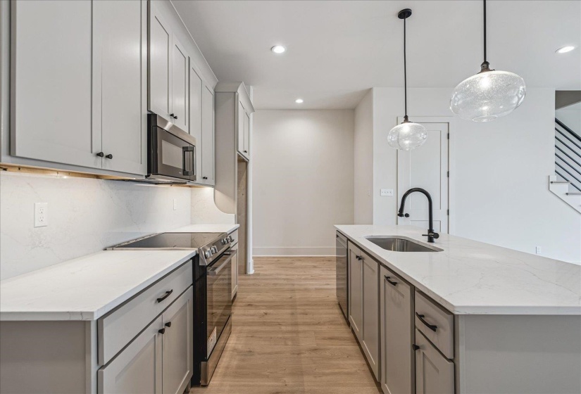 Contemporary kitchen featuring light gray cabinetry, stainless steel appliances, and wood-finish flooring