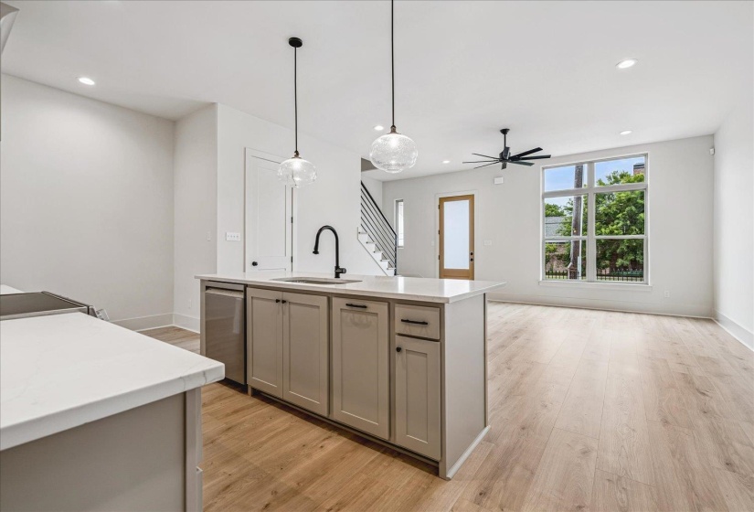 Open-concept living area featuring a kitchen island with stone countertops, a stainless steel dishwasher, and a black gooseneck faucet