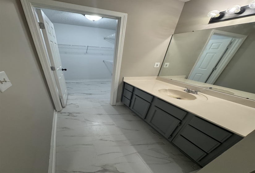 Bathroom featuring light marble finish floors, vanity, and a spacious closet