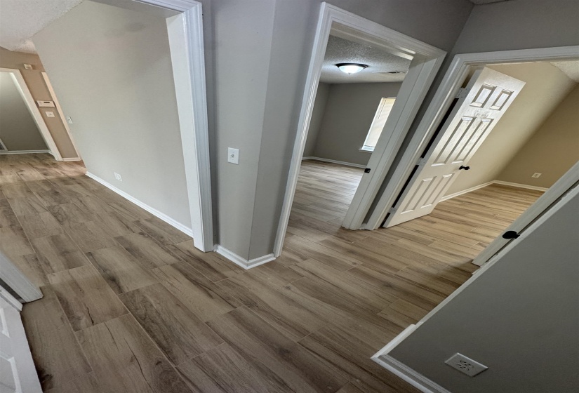 Corridor with light wood-type flooring and a textured ceiling