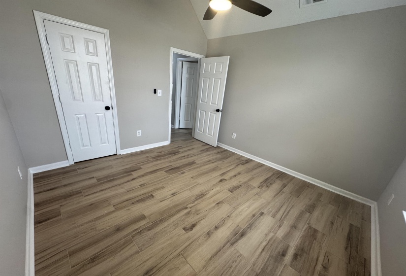 Unfurnished bedroom with lofted ceiling, light wood finished floors, and a ceiling fan