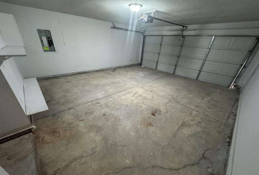 Garage featuring electric panel and a garage door opener