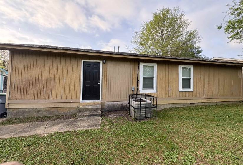 Vertical siding exterior featuring a dark entry door and two white-framed windows