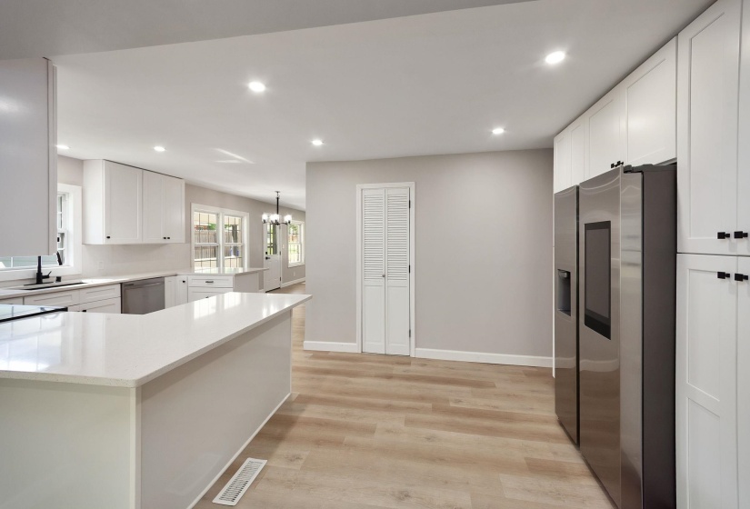 Open-concept kitchen with a large central island, white shaker-style cabinetry, and stainless steel appliances