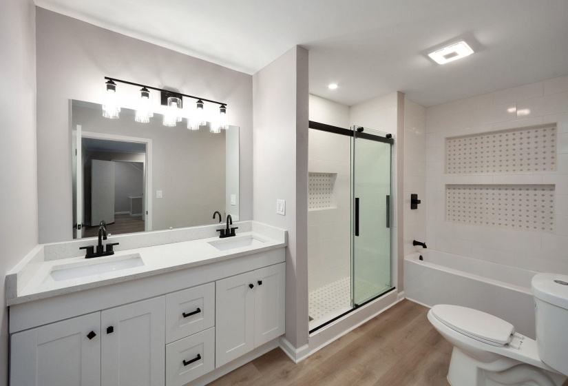 Bathroom featuring a dual vanity with white cabinetry and countertops, a large mirror, and black fixtures