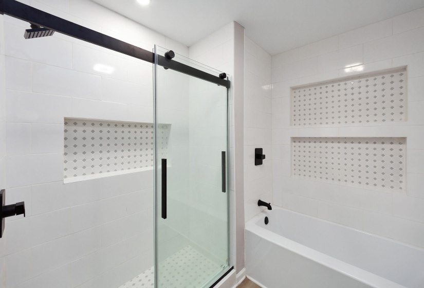 Modern bathroom featuring a walk-in shower with a sliding glass door, matte black hardware, and a rainfall showerhead