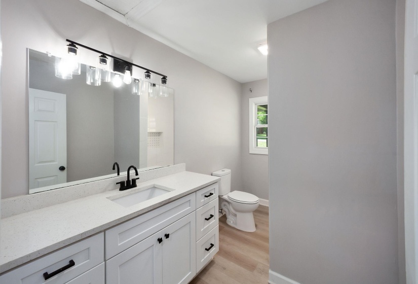 Bathroom featuring a white vanity with quartz countertop, integrated sink, and matte black fixtures