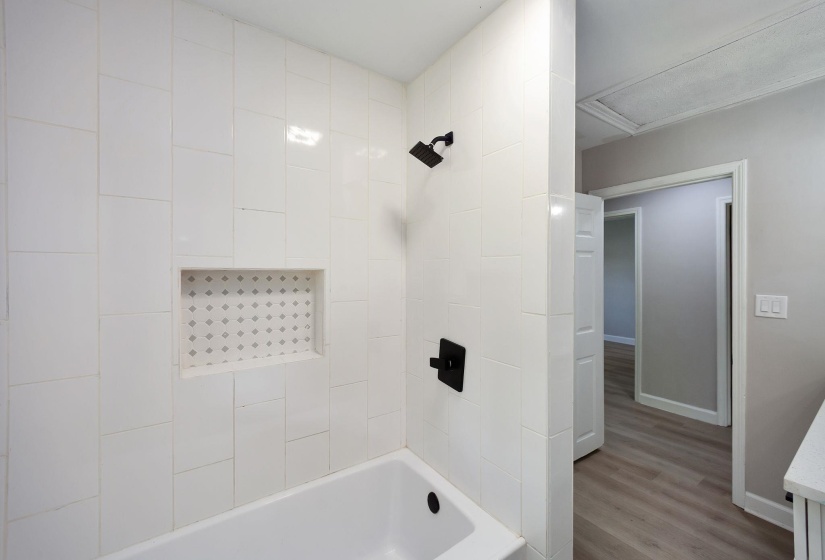 Bathtub with white tile surround featuring a tiled niche