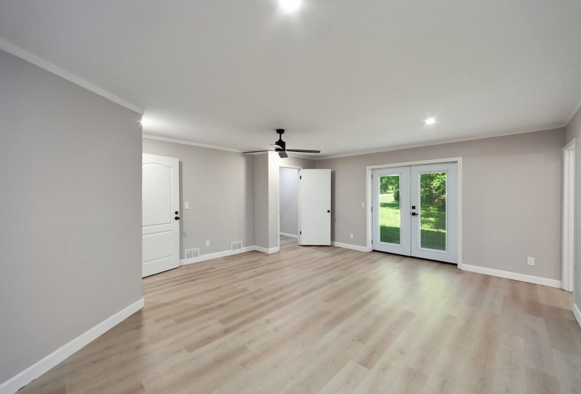 Spacious interior room featuring light wood-finish flooring, neutral wall tones, and crisp white trim