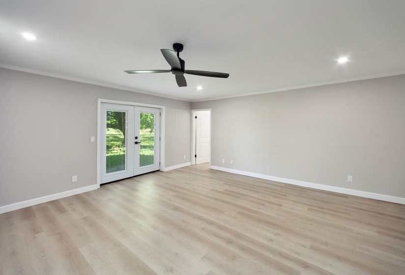 Spacious room featuring light wood-finish flooring, light grey walls, and white crown molding