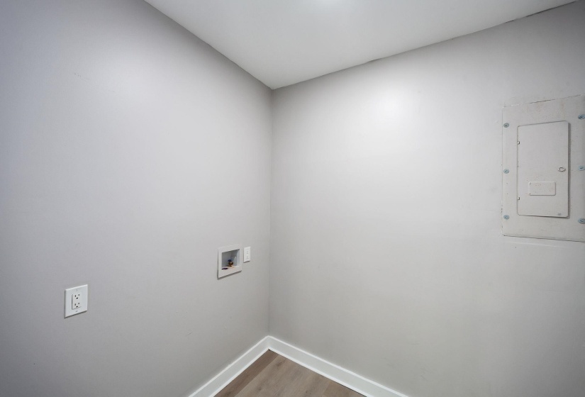 Utility room with light gray walls, white baseboards, and wood-finish flooring