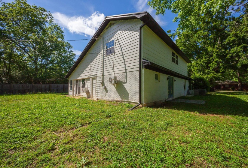 Rear exterior featuring a painted brick foundation, light-colored siding, and a dark roofline
