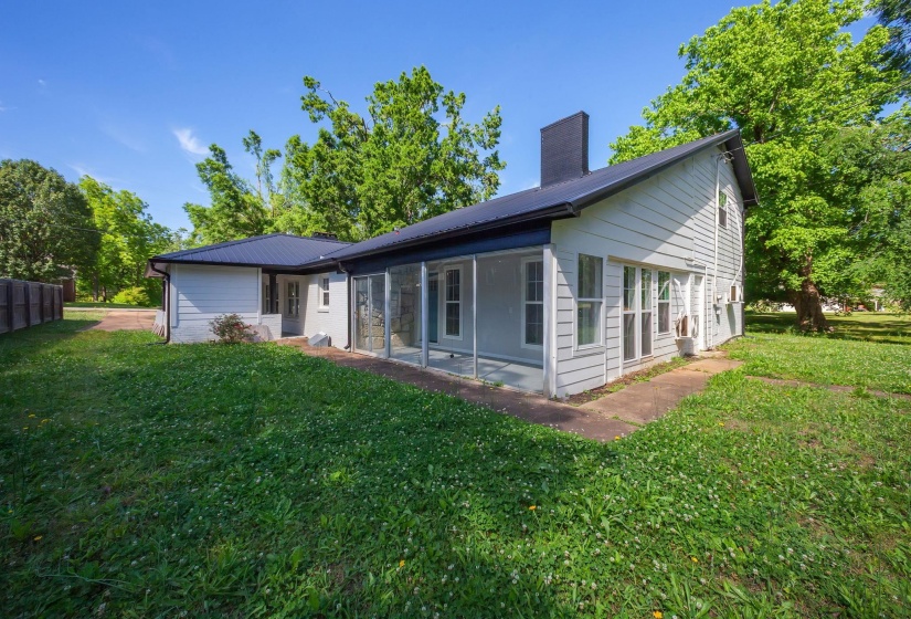 Exterior featuring white siding, a dark metal roof, and a screened-in porch