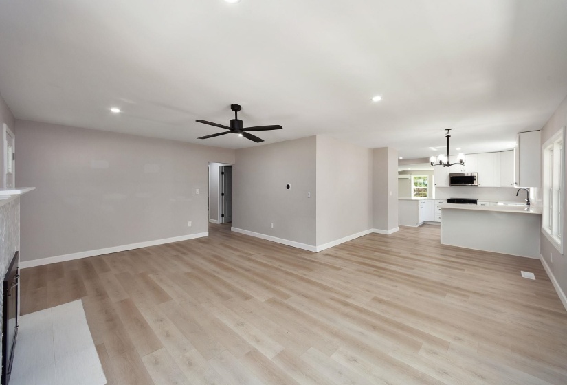 Spacious open-concept living area featuring light wood-finish flooring and recessed lighting