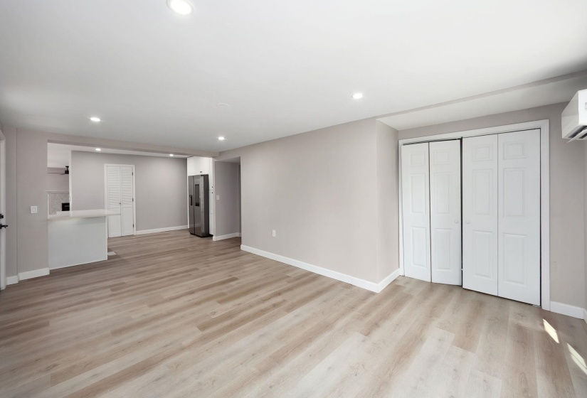 Open-concept living space with light wood-finish flooring, recessed lighting, and neutral wall tones