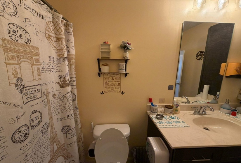 Bathroom featuring a single vanity with an integrated sink, coordinating countertop, and a wall-mounted mirror
