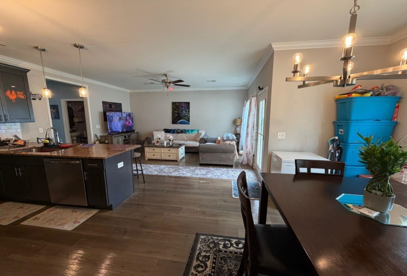 Open-concept living area featuring rich wood-finish flooring, a kitchen island with a granite-style countertop, and stainless steel appliances