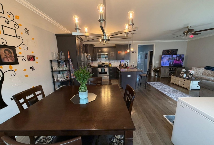 Dining area featuring a dark wood-finish table with coordinating chairs, crown molding, and a modern linear chandelier