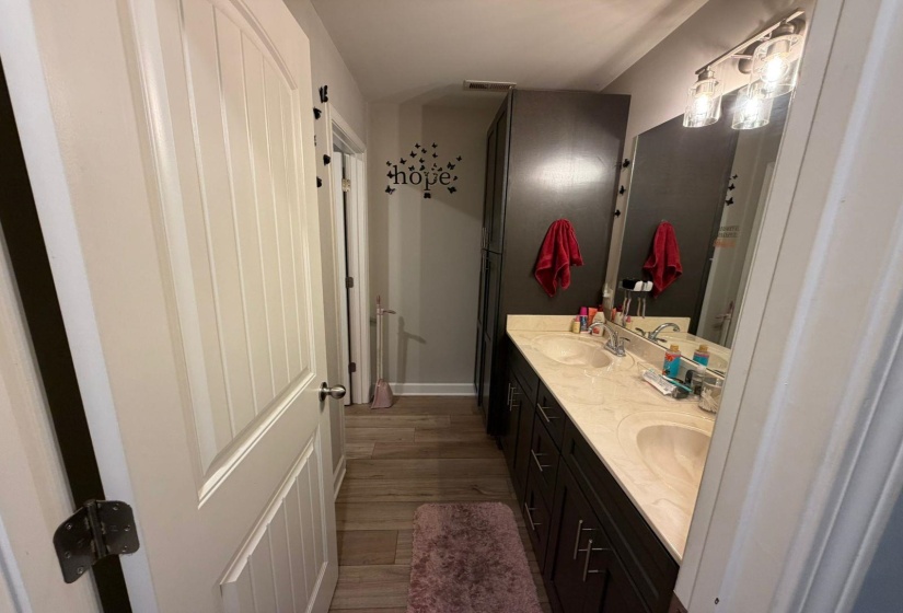 Dual vanity with integrated sinks and a light-toned countertop, set against wood-finish flooring