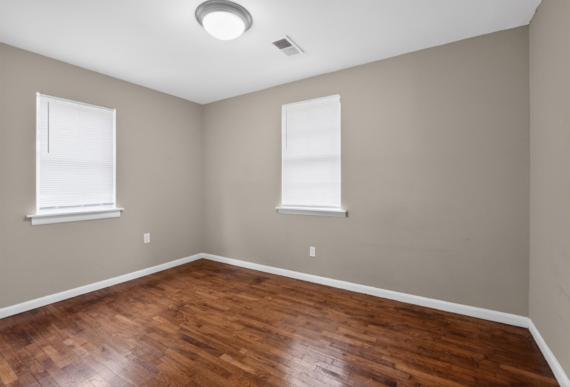 Room featuring wood-finish flooring, neutral wall tones, and white trim
