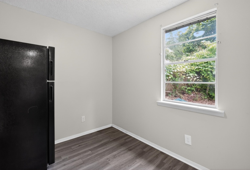 Corner room with a large window, wood-finish flooring, light gray walls, and white trim