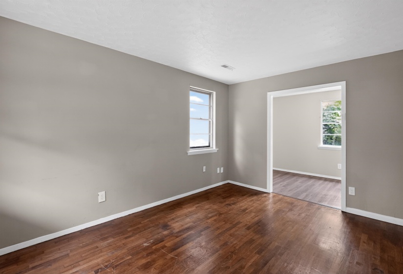 Interior room featuring rich wood-finish flooring, light gray wall paint, and white trim