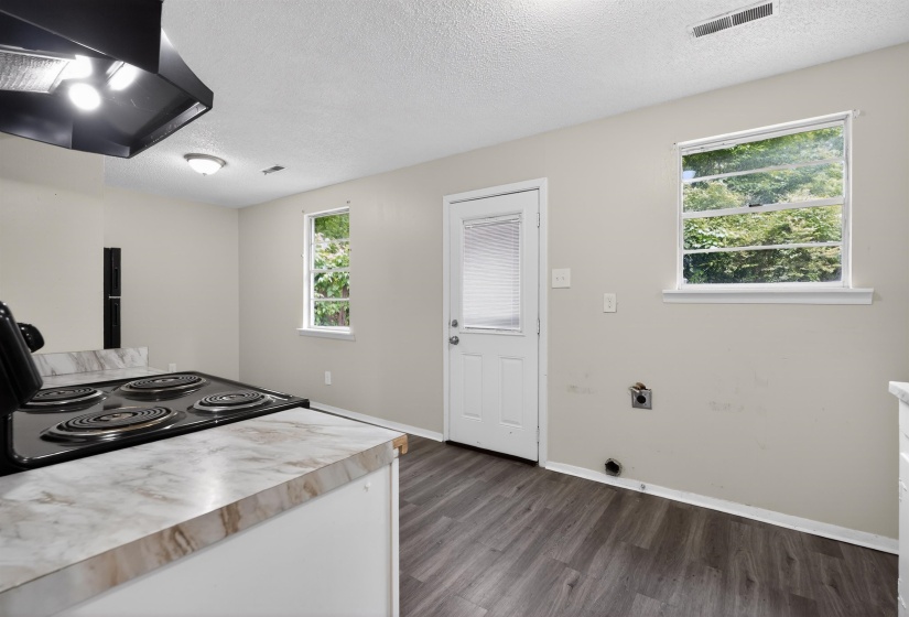 Kitchen space with wood-finish flooring, light-toned walls, and two windows