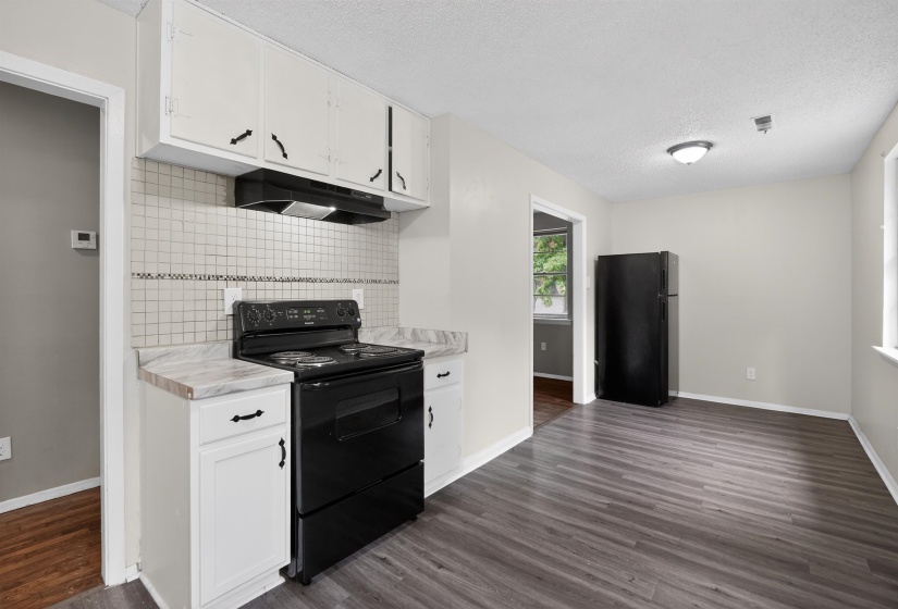 Kitchen featuring white cabinetry, gray wood-finish flooring, a black electric range with a matching range hood, and a black refrigerator