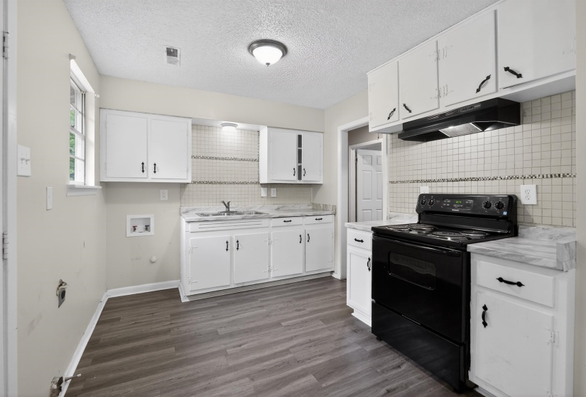 Kitchen featuring wood-finish flooring, white cabinetry, a black electric range with coordinating range hood, and a tile backsplash