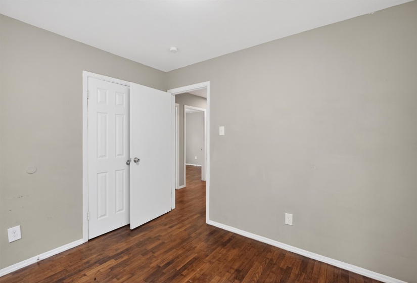 Interior room featuring wood-finish flooring, light gray wall paint, and white baseboards