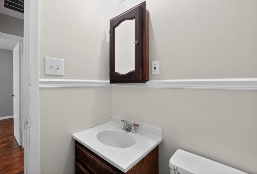 Bathroom vanity with a white countertop and integrated sink, complemented by a dark wood-finish cabinet