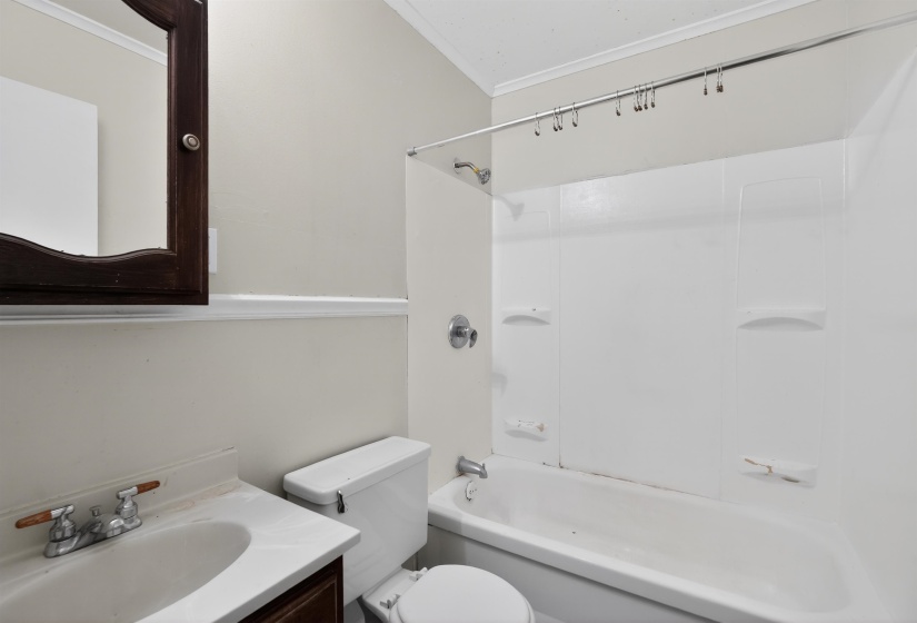 Bathroom featuring a white bathtub, integrated shower, and a dark wood-finish vanity with a white countertop